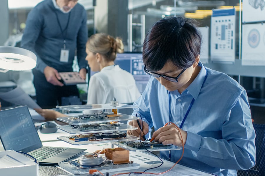 An Asian male engineering works on a PCB board design.